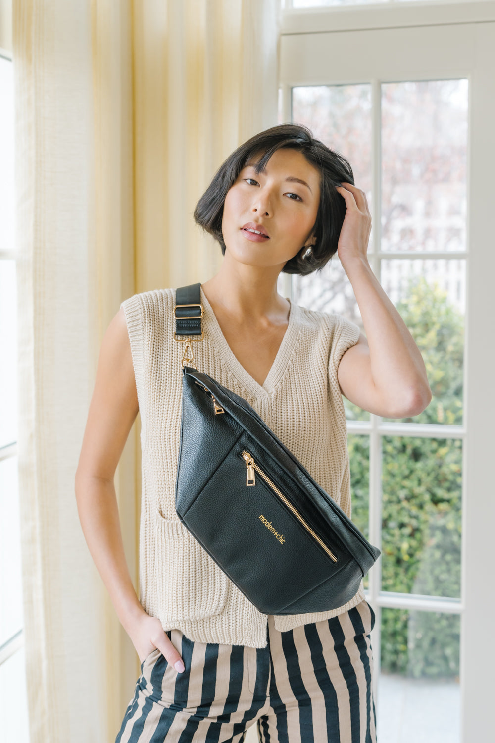 A woman wearing an oversized black sling bag across her torso.