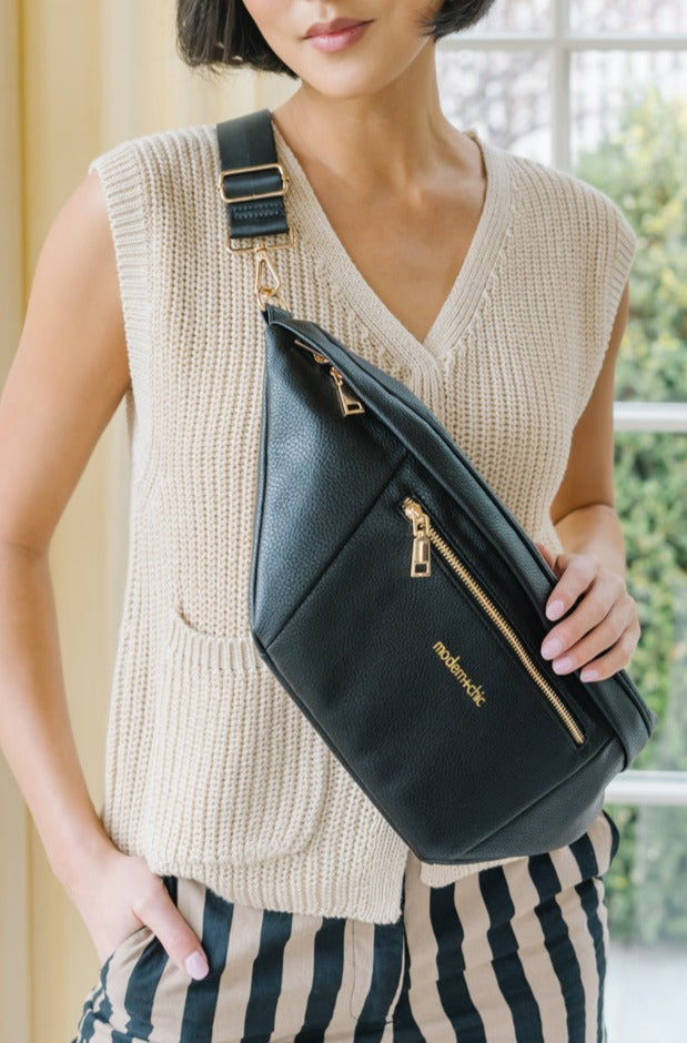 A woman wearing an oversized black sling bag across her torso.