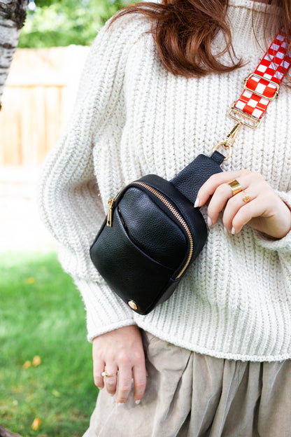 Woman wearing a red and white Modern+Chic Lizzie adjustable strap for crossbody bags on a black bag crossbody. 