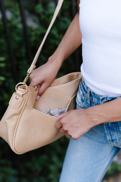 The back slot pocket of a cream crossbody