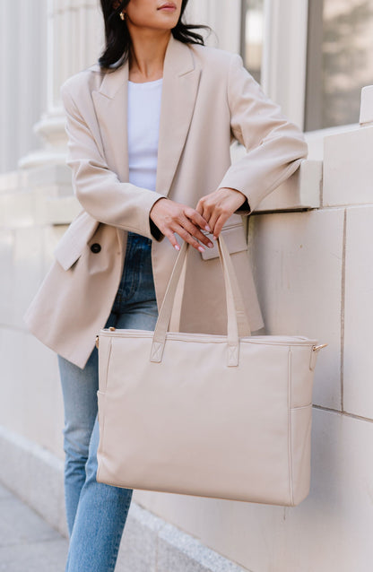 A woman holding a cream tote.