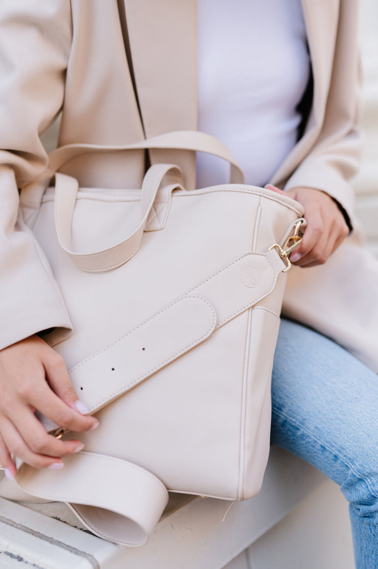 The cream tote has a belt-style adjustable bag strap.