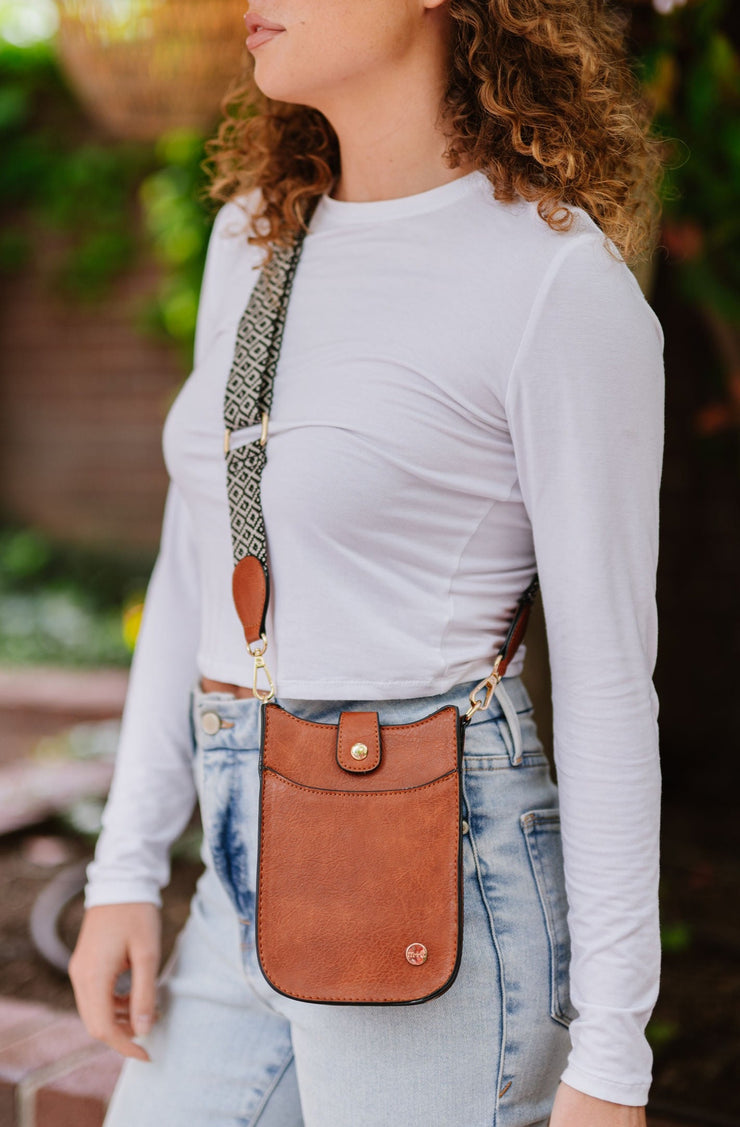 A woman wearing a small brown crossbody bag with a woven strap