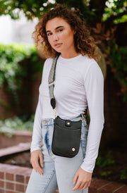 A woman wearing a small black crossbody bag with a woven strap