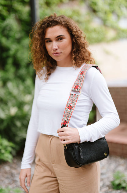 Woman wearing white shirt, tan pants and a Modern + Chic Gentry Vegan Leather Crossbody Bag in black.