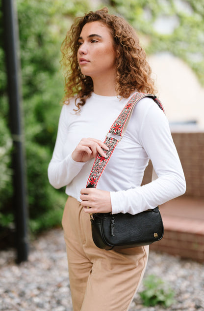 Woman wearing white shirt, tan pants and a Modern + Chic Gentry Vegan Leather Crossbody Bag in black.
