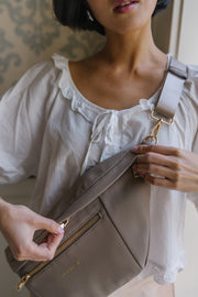 The taupe sling bag has two zipper pulls so it can be worn on either shoulder.