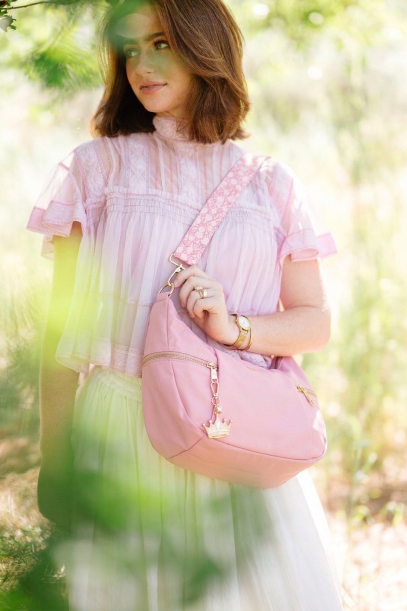 Woman holding a pink Modern + Chic Parker Crescent Crossbody Bag for Women in a forest setting.