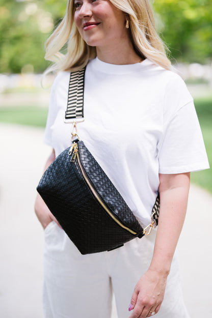 Woman wearing a white t-shirt and a black criss cross style Modern + Chic Rory Oversized Belt Bag for Women with a gold zipper and hardware crossbody.
