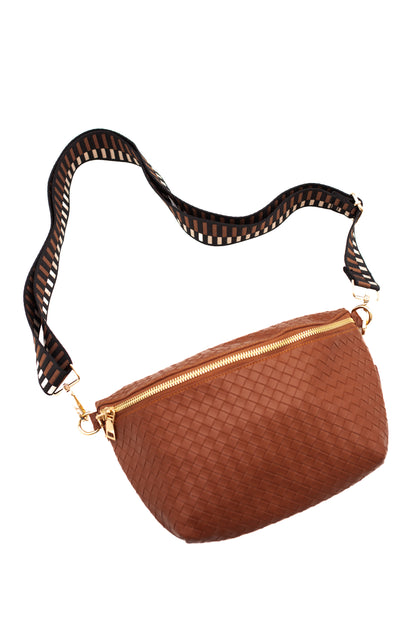 A camel criss cross style Modern + Chic Rory Oversized Belt Bag for Women with a gold zipper and hardware and a black,camel and white printed strap on a white background.